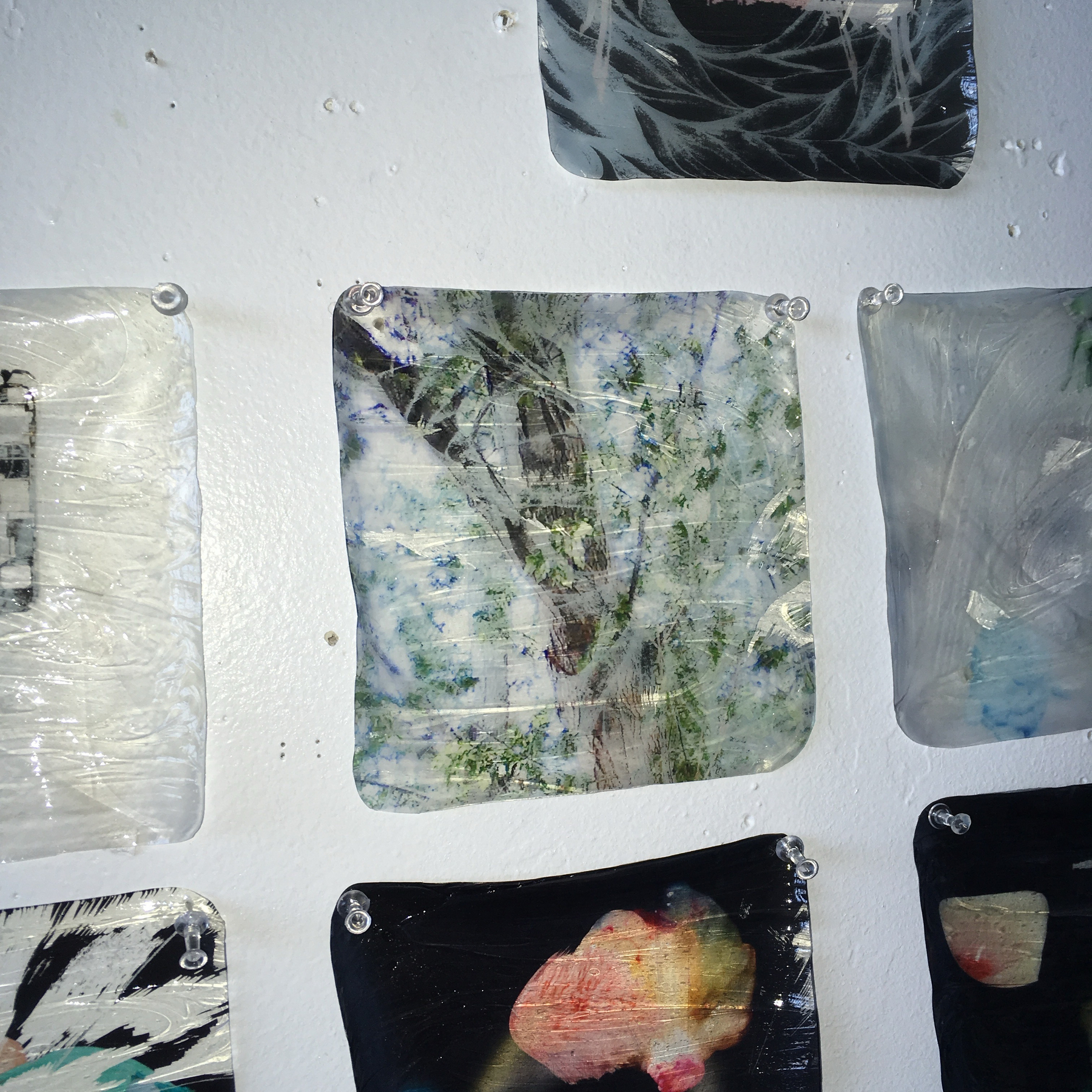 Several abstract art pieces are displayed on a white wall.