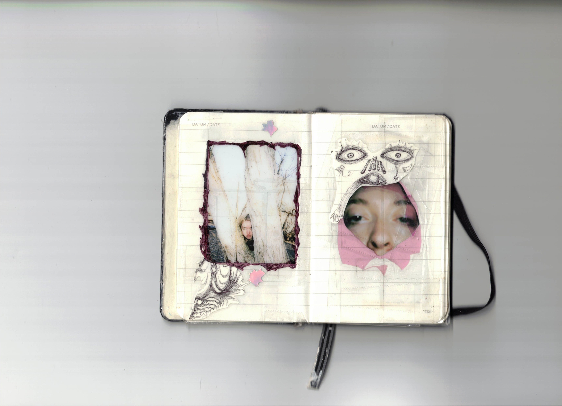 Auto-generated description: An open notebook features two cut-out sections revealing parts of a person's face beneath, with intricate black-and-white drawings surrounding the cut-outs.